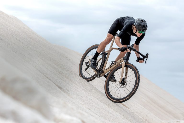 Man riding gravel bicycle across the sand. Get your bike at Central Cycles today!