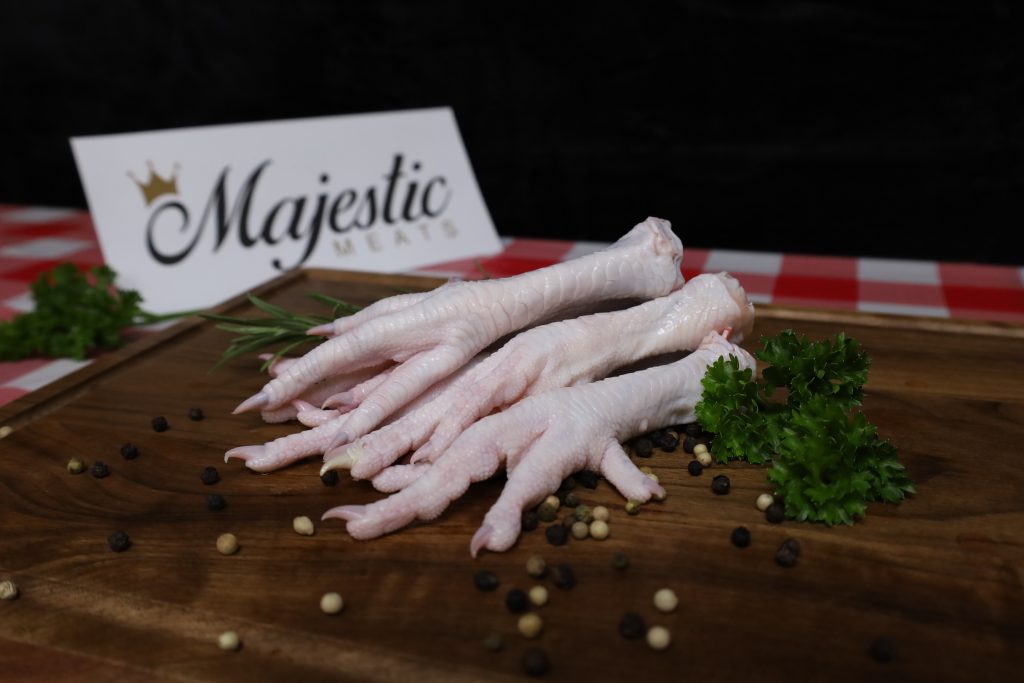 Majestic Meats chicken feet on wooden board with parsley and peppercorns.